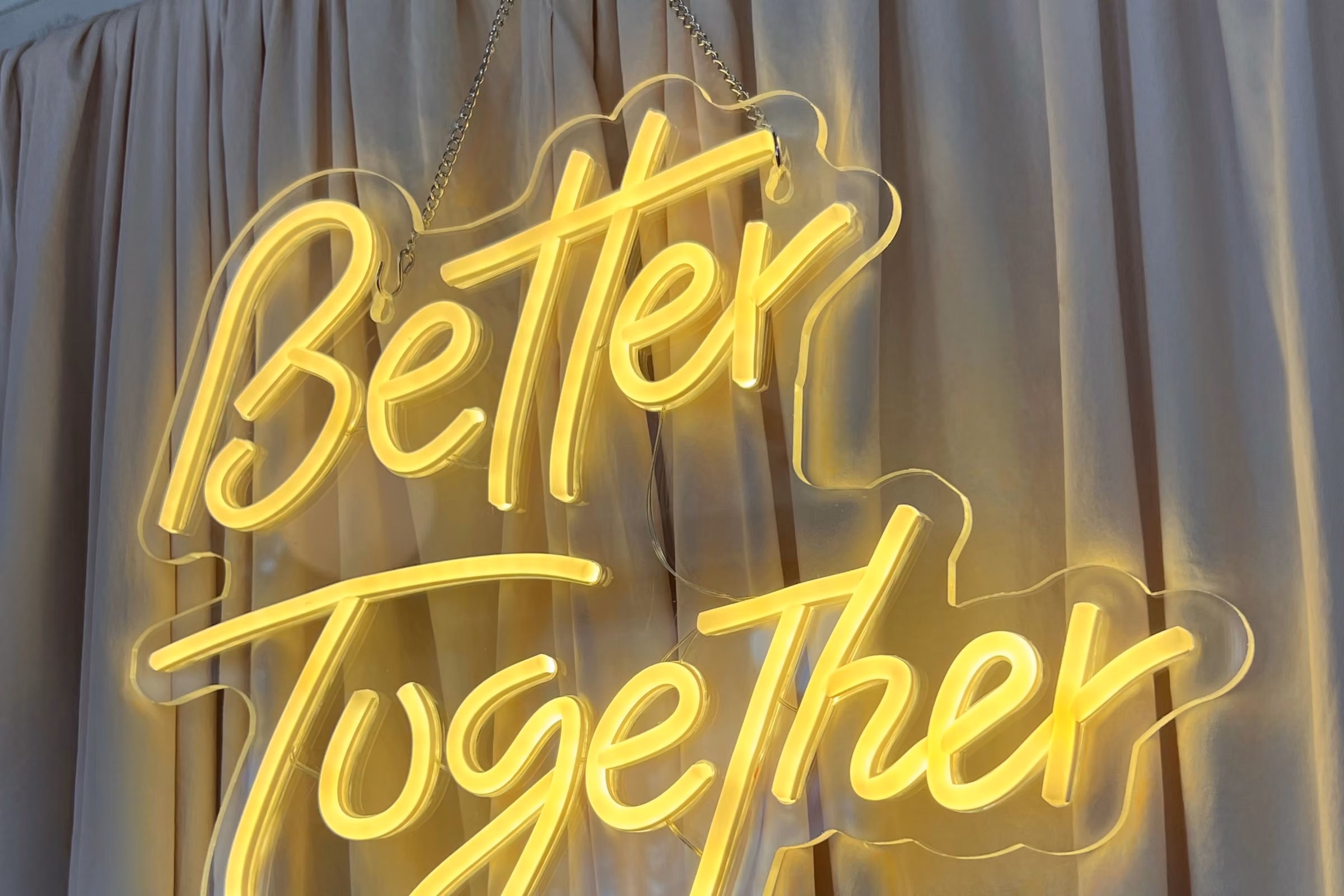 Жёлтая неоновая вывеска Better Together на бежевой шторе фотозоны